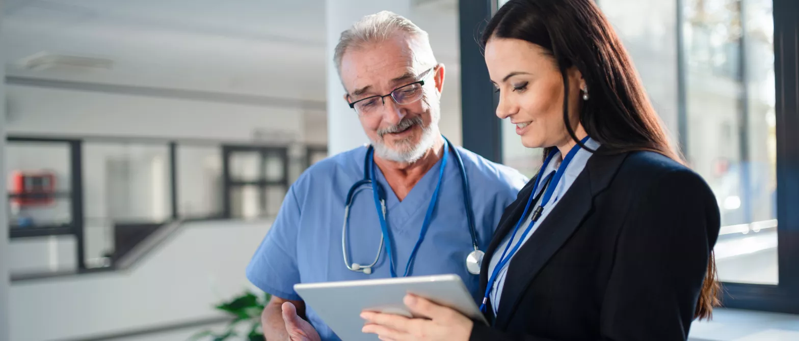 Health professionals in scrubs talks to woman with clipboard