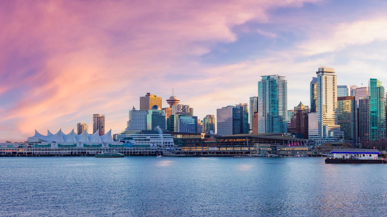 Skyline of a city with modern skyscrapers under a vibrant pink and purple sunset