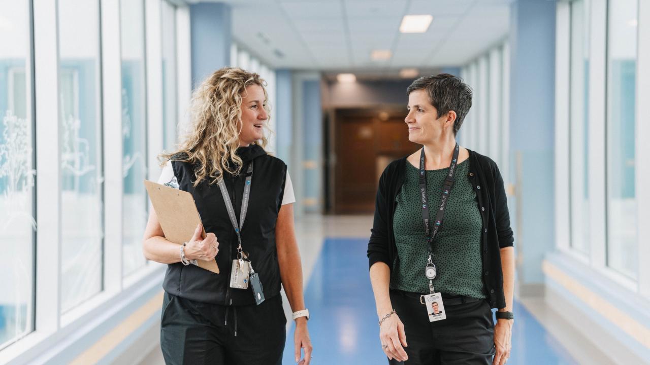 Two health care workers speaking in a hallway