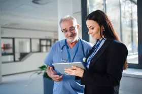 Health professionals in scrubs talks to woman with clipboard