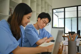 Two employed student nurses working on a laptop