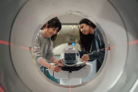 Two smiling staff members using medical machine