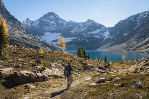 Hiker approaches alpine lake surrounded by mountains