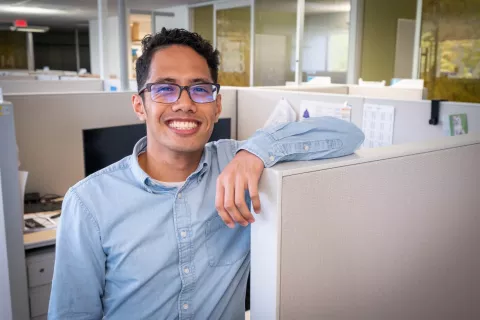 Smiling man leaning on cubicle wall