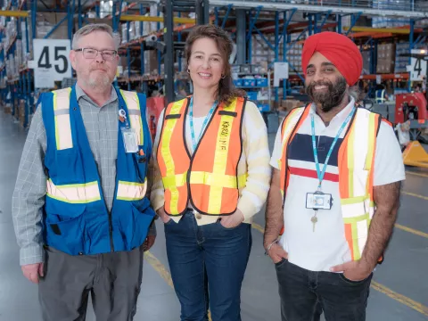 Two men and one woman in warehouse smiling