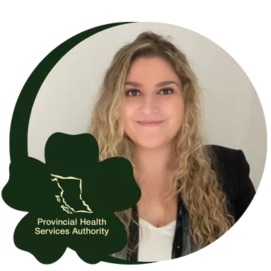 A woman with long, curly blonde hair is smiling warmly. They are wearing a black blazer over a white top