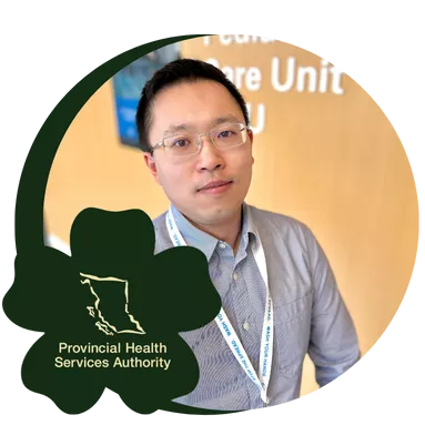 A man wearing glasses and a striped shirt stands in front of a wall with "Pediatric Intensive Care Unit" written on it