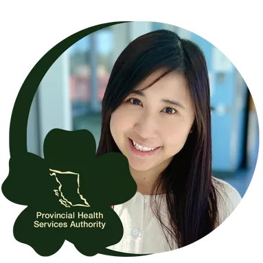 Smiling woman with long dark hair wearing a light blouse stands in a sunlit hallway