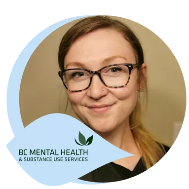 A woman with glasses smiles in a warmly lit room