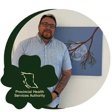 An Indigenous Health employee posing next to a painting