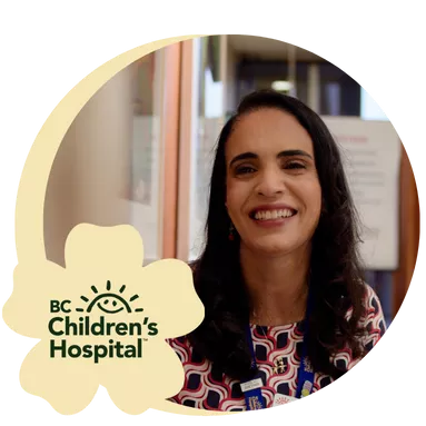 A woman with long dark hair is smiling warmly in an indoor setting