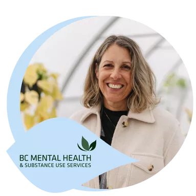 An activity worker posing for a photo in a greenhouse.