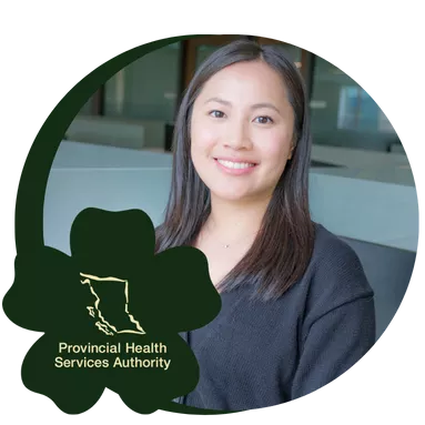 Smiling woman with long hair wearing a black cardigan stands in a modern office