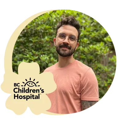 A man with glasses smiling for a photo outside