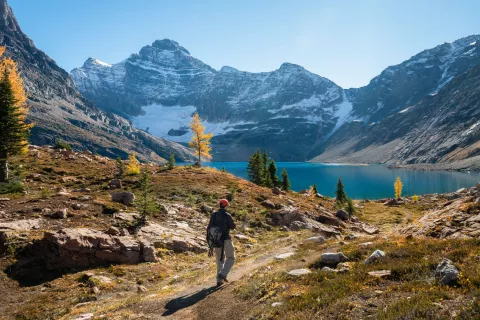 Hiker approaches alpine lake surrounded by mountains